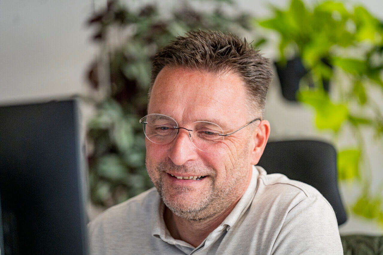 Willem, collega van Awesems, aan het werk achter de computer. Close-up.