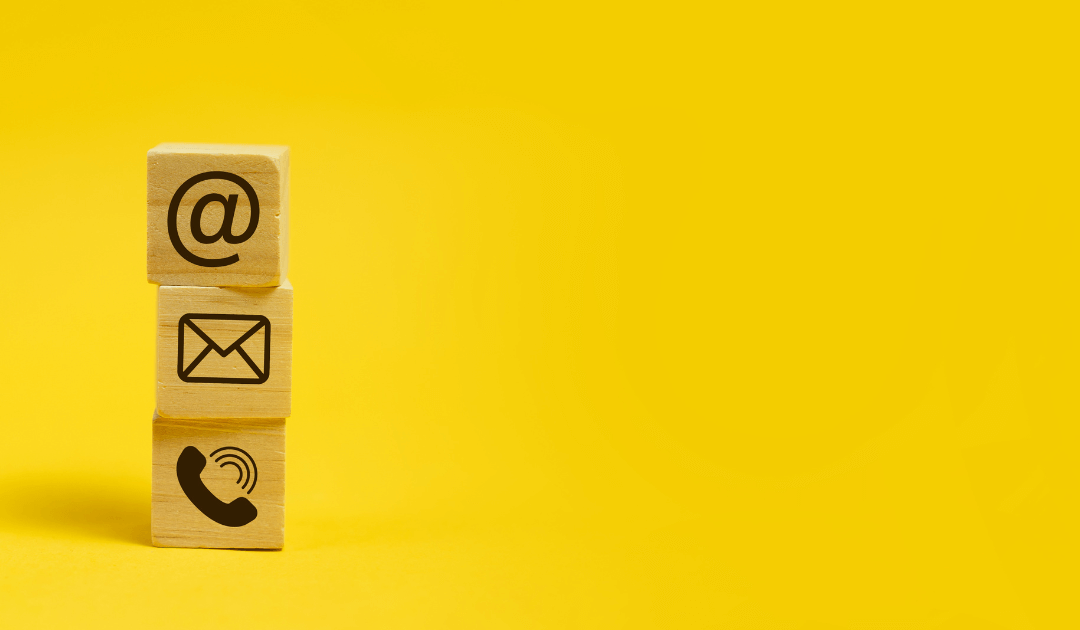 drie houten blokken speels op elkaar gestapeld. Onderste blok icoon van telefoon, middelste blok icoon van post, bovenste blok icoon van mail.